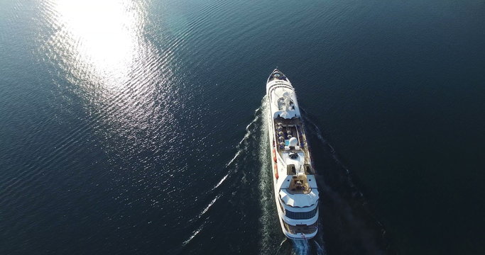 Aerial view of luxury medium cruise ship sailing from port on sunrise