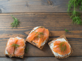 Drei Vollkornbrot-Sandwiches mit Räucherlachs von oben mit Text