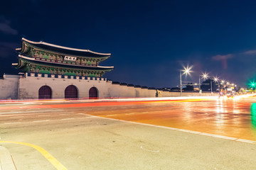 Night shot of Gwanghwamun gate of Gyeongbokgung Palace in Seoul, South Korea with taillights and headlights of cars in front of it