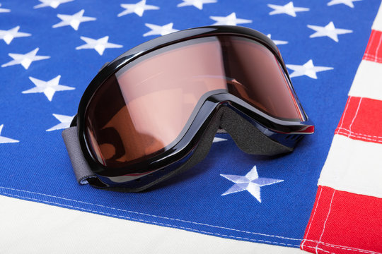 Winter sports implements over USA flag - snowboard or ski goggles