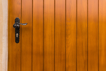 
Detail einer modernen Außentür aus Echtholz mit Türgriff aus Schmiedeeisen und Schutzbeschlag
