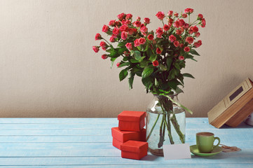 Bouquet of roses, gifts, cup of coffee and card