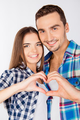 Cheerful couple in love embracing each other gesturing a heart