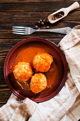 
lunch or dinner , meatballs with rice , carrots, onions , spices and tomato sauce on a wooden background