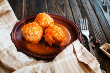 
lunch or dinner , meatballs with rice , carrots, onions , spices and tomato sauce on a wooden...