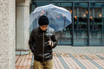 An Asian Man in a Brown Jacket is Strolling a Street 