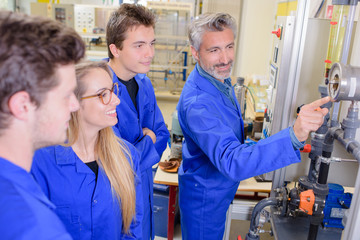 Teacher pointing to machine, everyone smiling