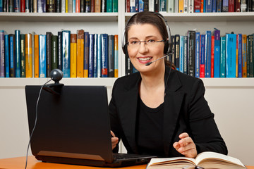 Smiling woman with headphone, computer and webcam in her office, consultant, adviser, teacher,...