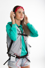 Young brunette female student standing and listening to music from your device. Beautiful young backpacker