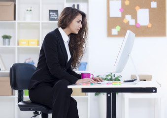 Beautiful young business woman in her office working on computer,shallow depth of field
