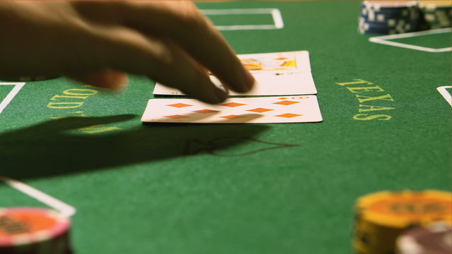 Poker - Dealer hands out cards on a green table (close up)
