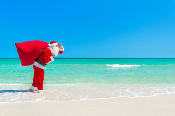 Santa Claus with big Christmas sack at tropical ocean beach