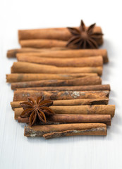 Cinnamon sticks and anise stars on white wooden background