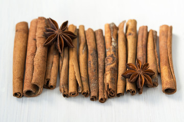 Cinnamon sticks and anise stars on white wooden background