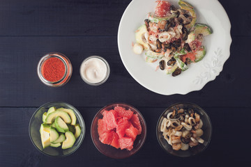 Seafood salad with ingredients on the dark wooden table