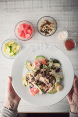 Seafood salad in the hand with blurred ingredients vertical