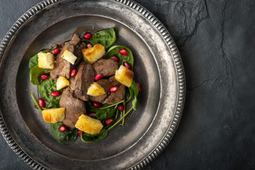 Salad with chicken liver and spinach on the vintage metal plate