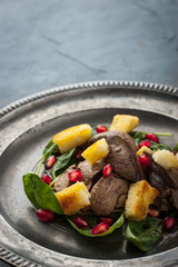 Salad with chicken liver and spinach on the vintage metal plate vertical