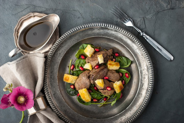 Salad with chicken liver and spinach on the vintage metal plate top view