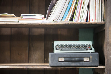 Wooden bookshelf with books and antique typewriter