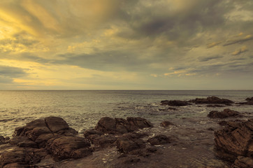 Obraz premium Dramatic sunset at the ocean with boulder rocks