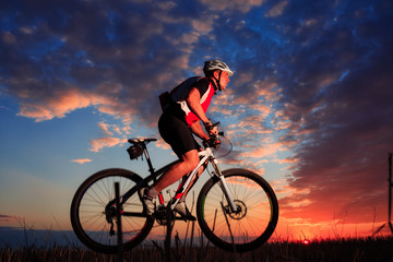 Man with bicycle at the sunset outdoor