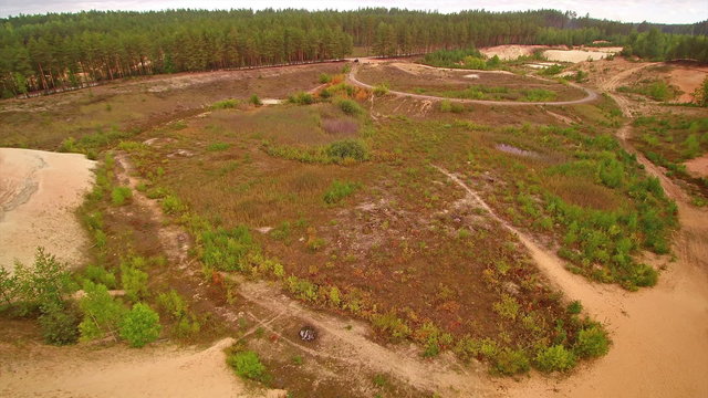The grassy area of the sand quarry in Piusa. The area is filled trees on the side and the white sands for quarrying