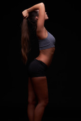 Fototapeta na wymiar Beautiful young girl on a dark background is engaged in fitness