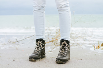 Female feet in blue jeans and black winter boots standing in the