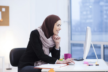 Beautiful Arabic business woman working on computer. Woman in her office, shallow depth of field