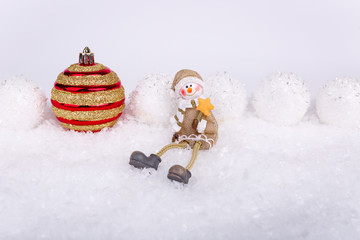 Xmas or new year composition with holiday decorations - snowballs lie in the line on snow and therebetween tree toy and little man sitting. White background. Christmas card