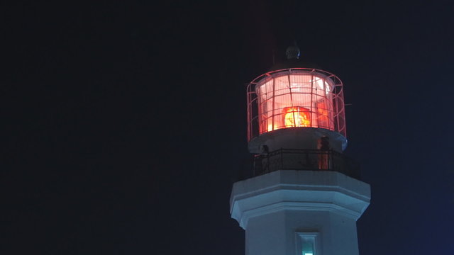 Lighthouse with red light at night, medium shot. Static, slow motion 60 fps.