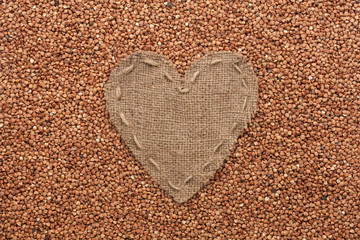 Frame in the shape of heart made of burlap with buckwheat
