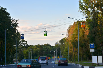 Cableway with colorful booths on the highway surrounded by trees in autumn