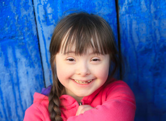 Young girl smiling on background of the blue wall.