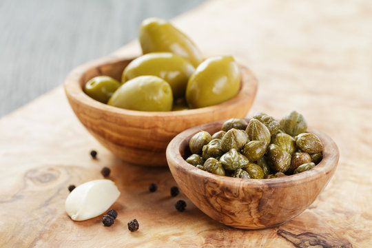 green huge olives and capers on wood table
