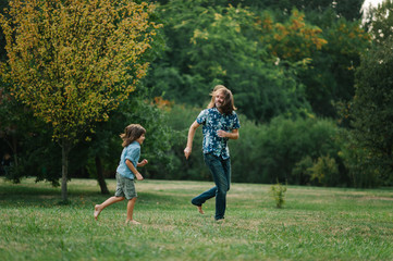 Fototapeta premium Happy young hipster family having fun while running, bowl, rising up, piggyback ride their children in park on summer sunset 