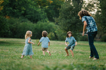 Fototapeta premium Happy young hipster family having fun while running, bowl, rising up, piggyback ride their children in park on summer sunset 