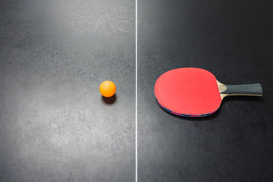 table tennis racket with orange ball on table