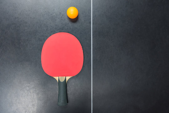 table tennis racket with orange ball on table