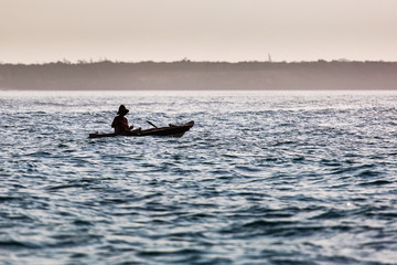 Fisherman in boat on ocean with big waves in Zanzibar