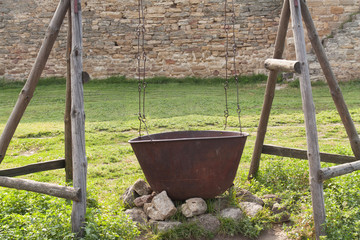 Old rust pot on the fire, tourists kettle on hot campfire. Camping historical photo.