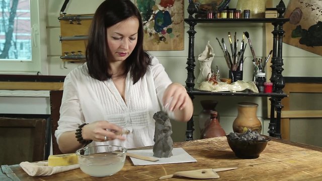 Artisan woman modelling a clay sculpture in a studio
