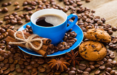Close-up of coffee cup with roasted coffee beans on wooden backg