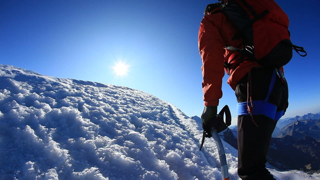 Mountaineer walks along the snowy ridge of Breithorn, on the Italy/Switzerland border, Europe.
