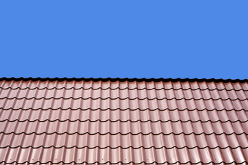 Gable roof of a house covered with metal tile isolated on blue background closeup