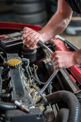 Obraz na płótnie Canvas Car mechanic in auto repair service, starting ignition plug