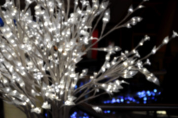 Blurred Christmas background: white bush with glowing lights.