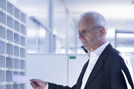 Businessman at pigeonhole in office