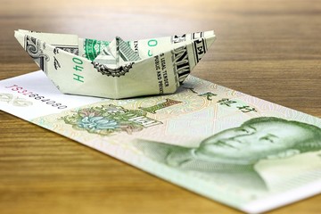 Papierboot aus einem US Dollar gefaltet auf chinesischer 1 Yuan Banknote